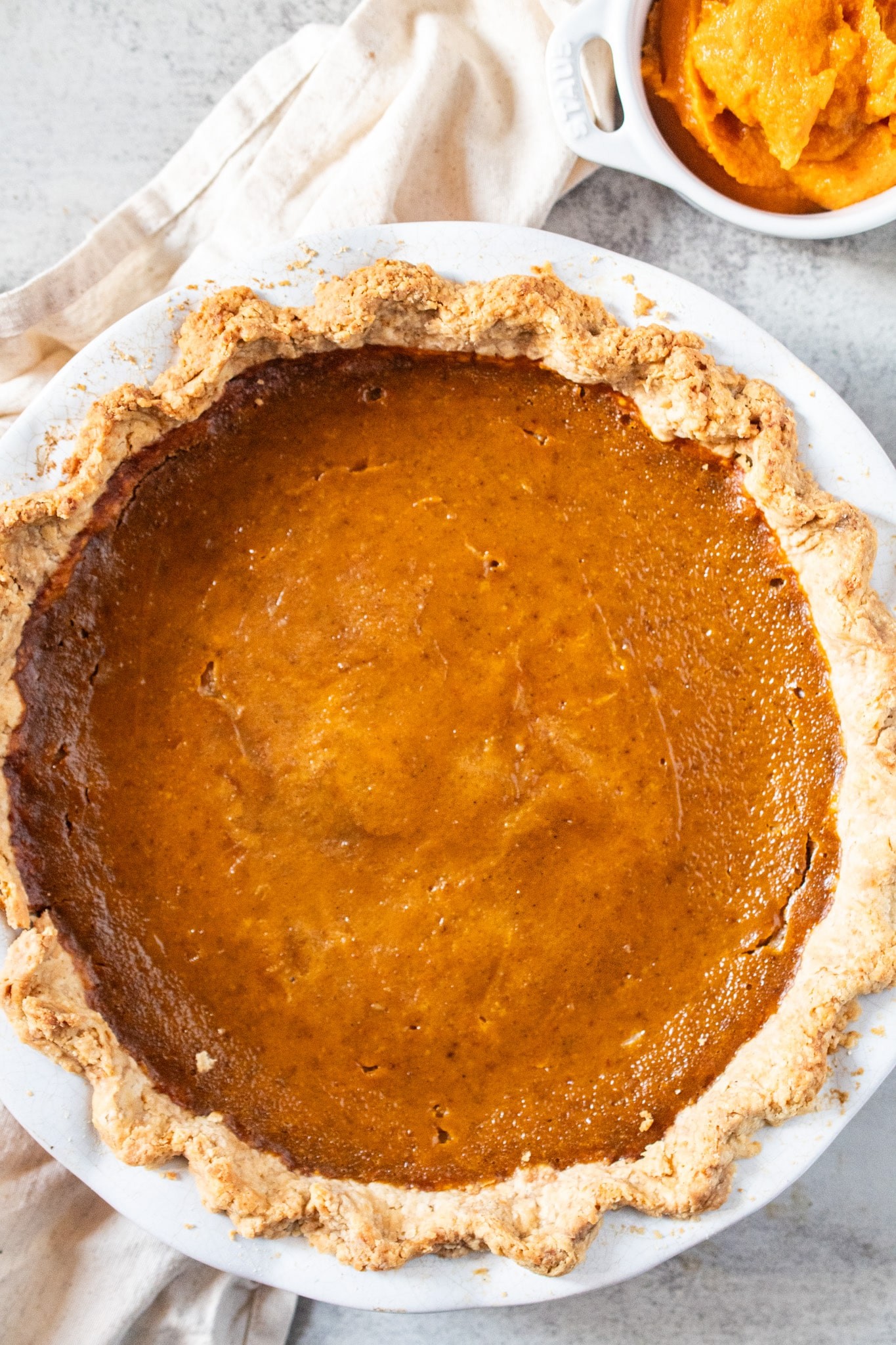 Homemade creamy pumpkin pie with flaky butter crust, whole pie and a slice