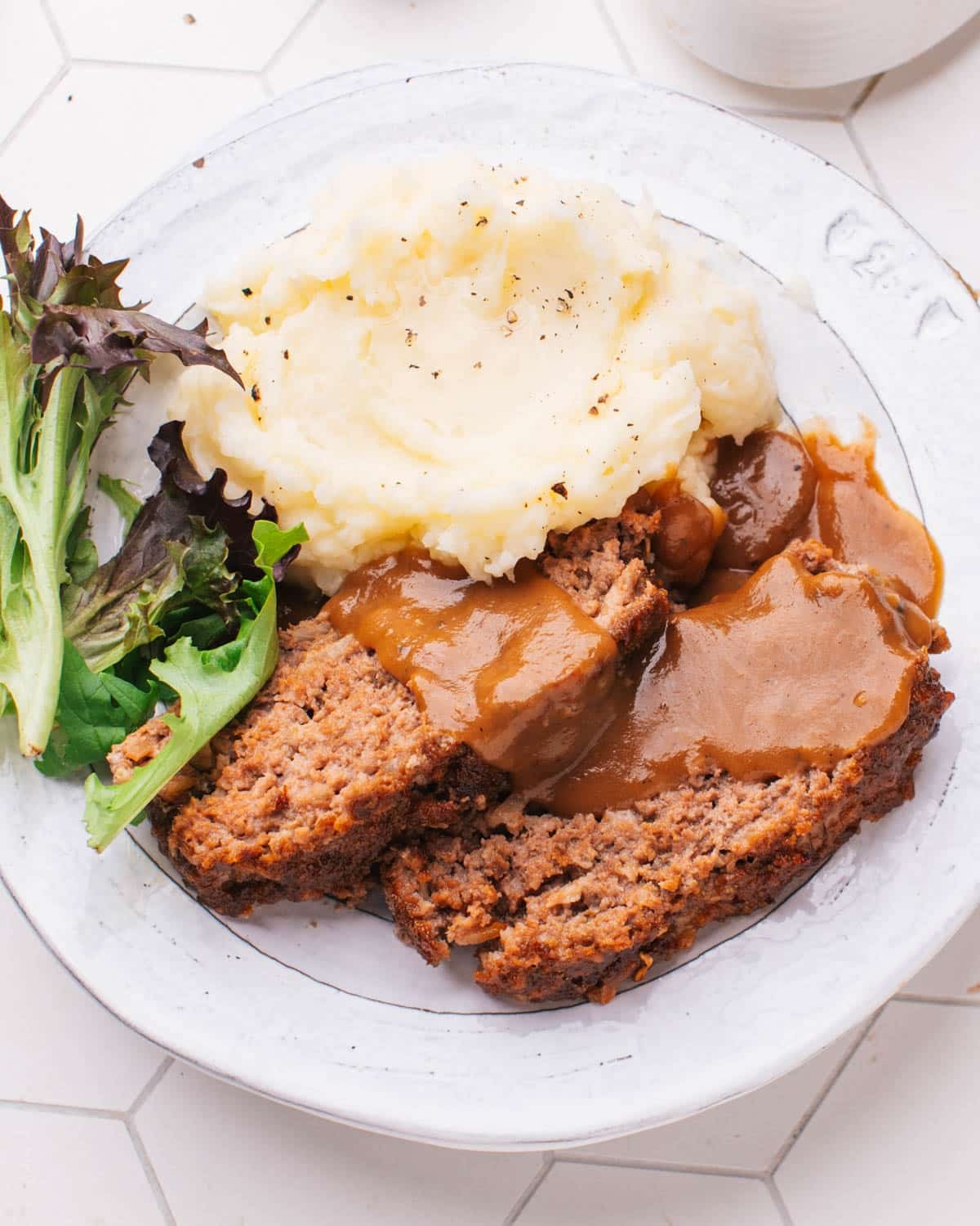 Classic smoky herb meatloaf with gravy and mashed potatoes, rustic setting, warm lighting