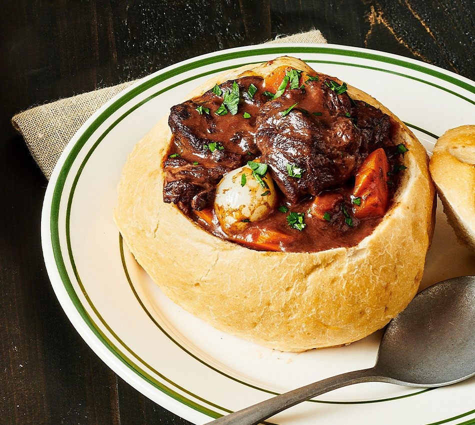 bowl of steaming beef stew with vegetables and crusty bread