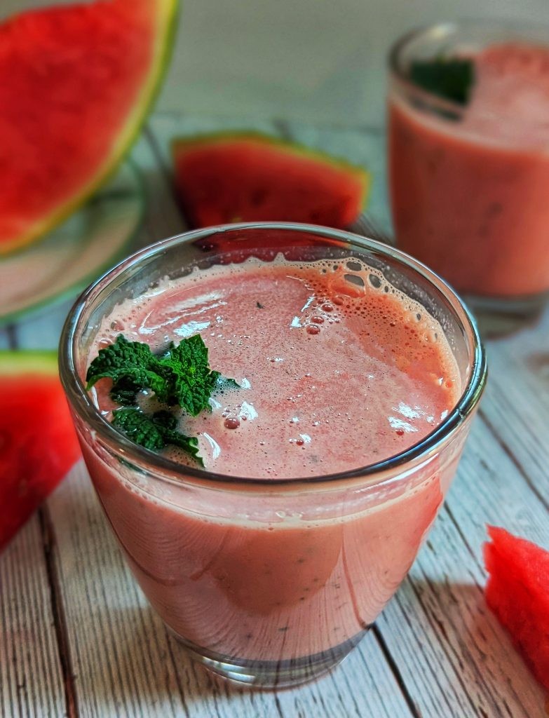 fresh watermelon lassi in a glass with watermelon slices and mint garnish