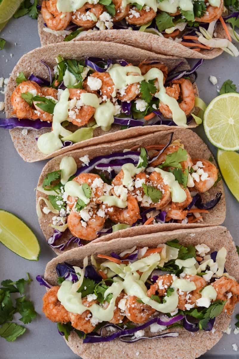 crispy shrimp tacos with avocado crema on a wooden serving board