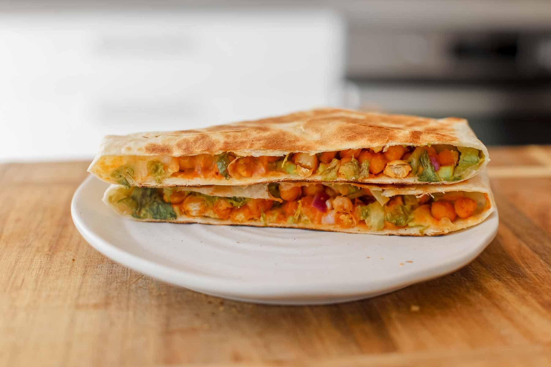 buffalo chickpea wraps on a wooden surface with avocado slices