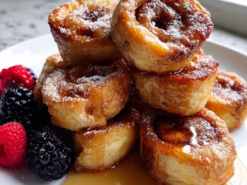 top-down view of cinnamon roll french toast bites with glaze on a white plate