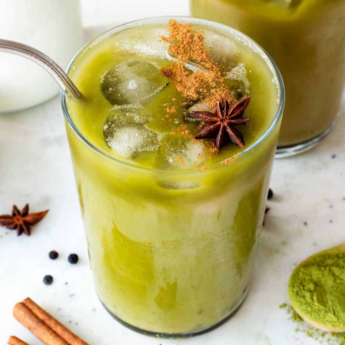 Matcha Chai Fusion Latte in a clear glass mug, garnished with cinnamon stick and star anise