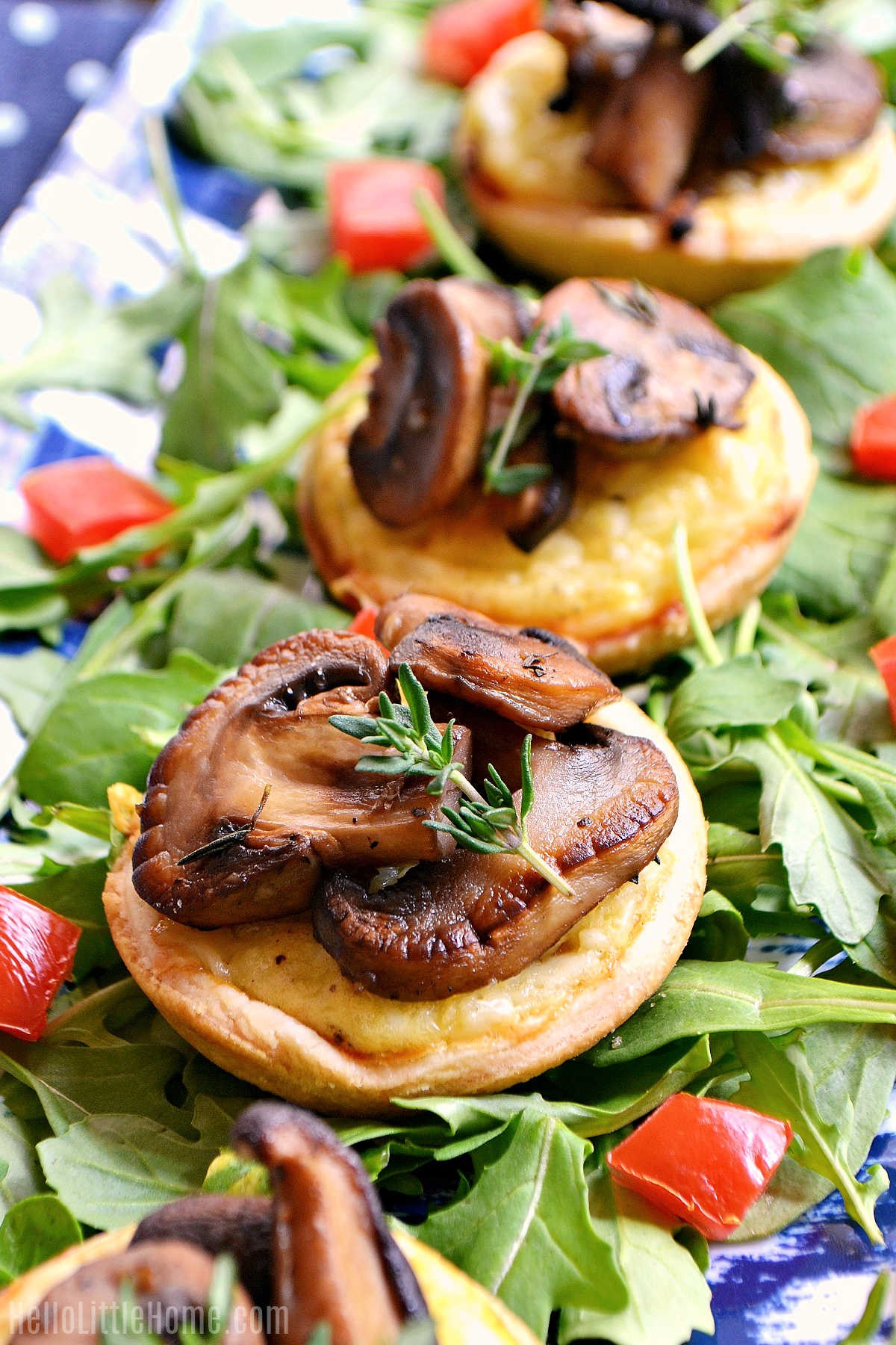 Close-up of golden brown mini cheese tarts on a wooden board with fresh herbs