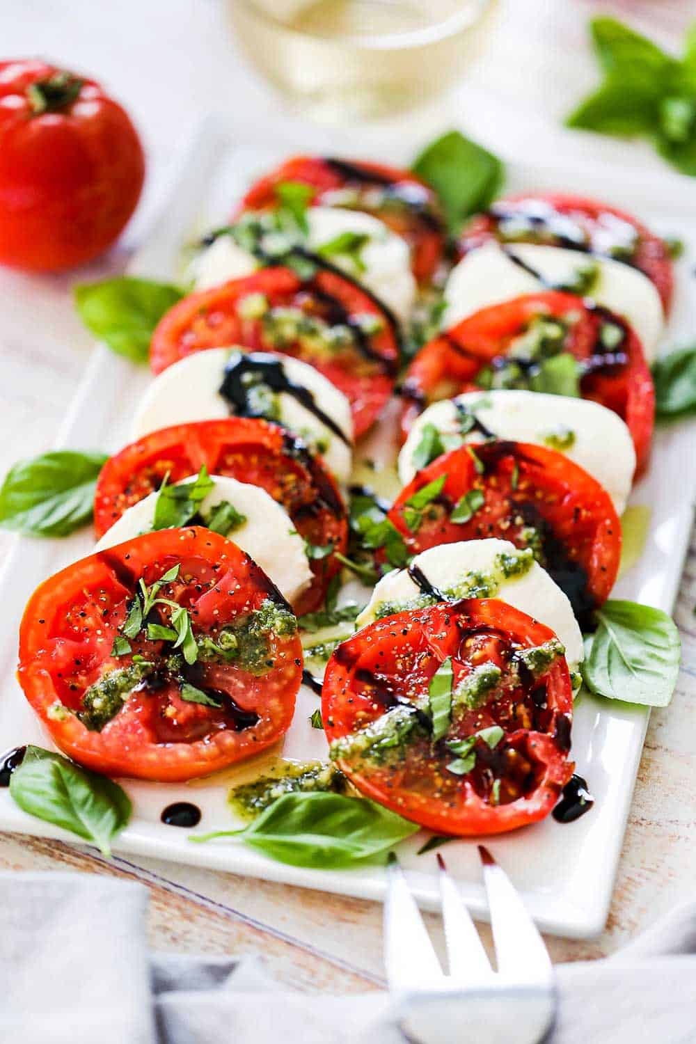 Caprese salad drizzled with white balsamic glaze, basil garnish