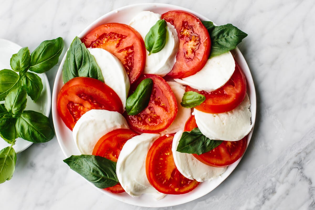 Caprese salad with fresh mozzarella, tomatoes, and basil on a white plate