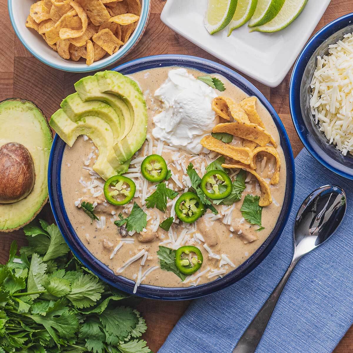 hearty white chicken chili in a bowl with toppings, side view, comfort food