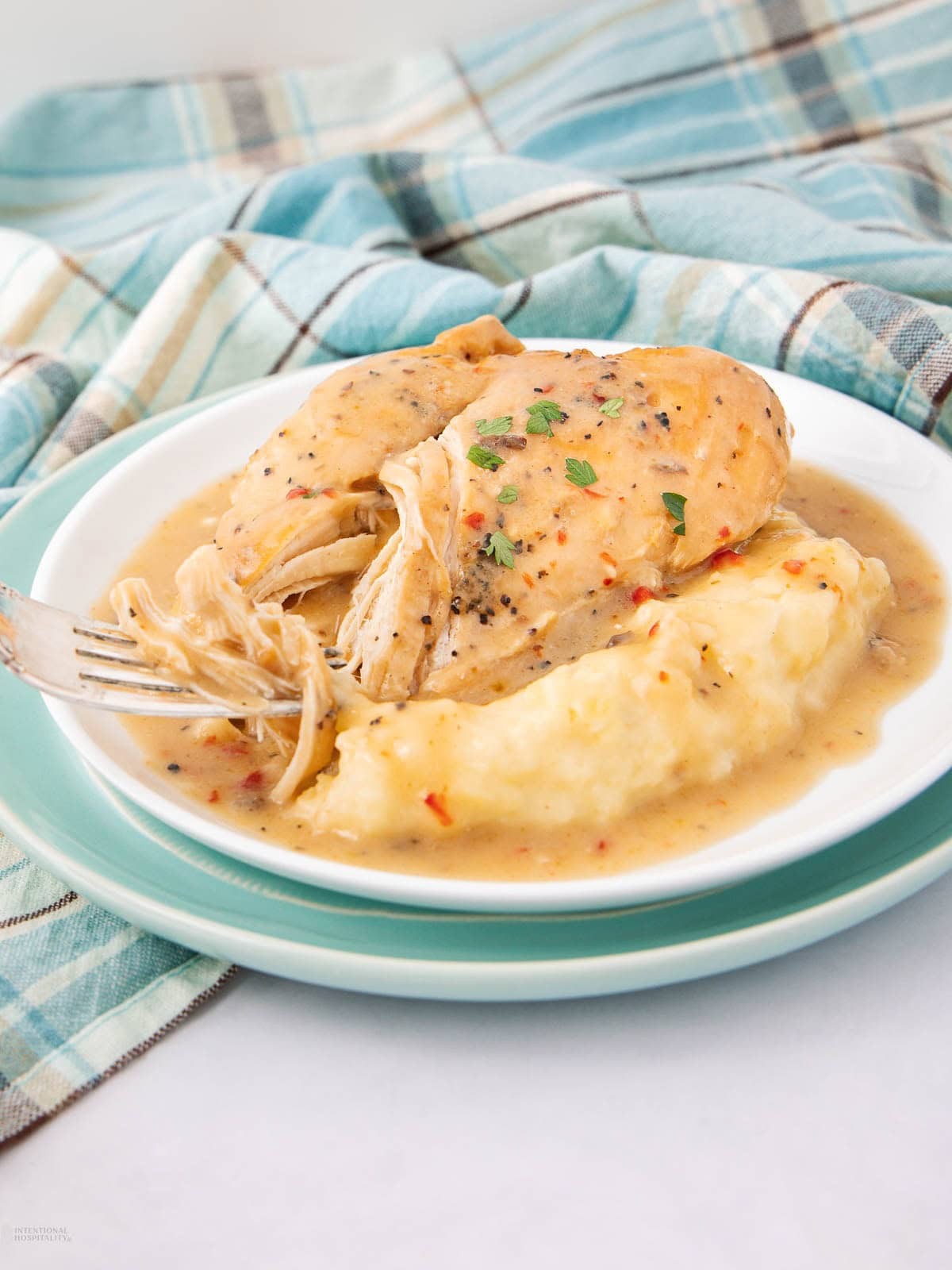 Crockpot chicken being served on a plate, cozy home setting