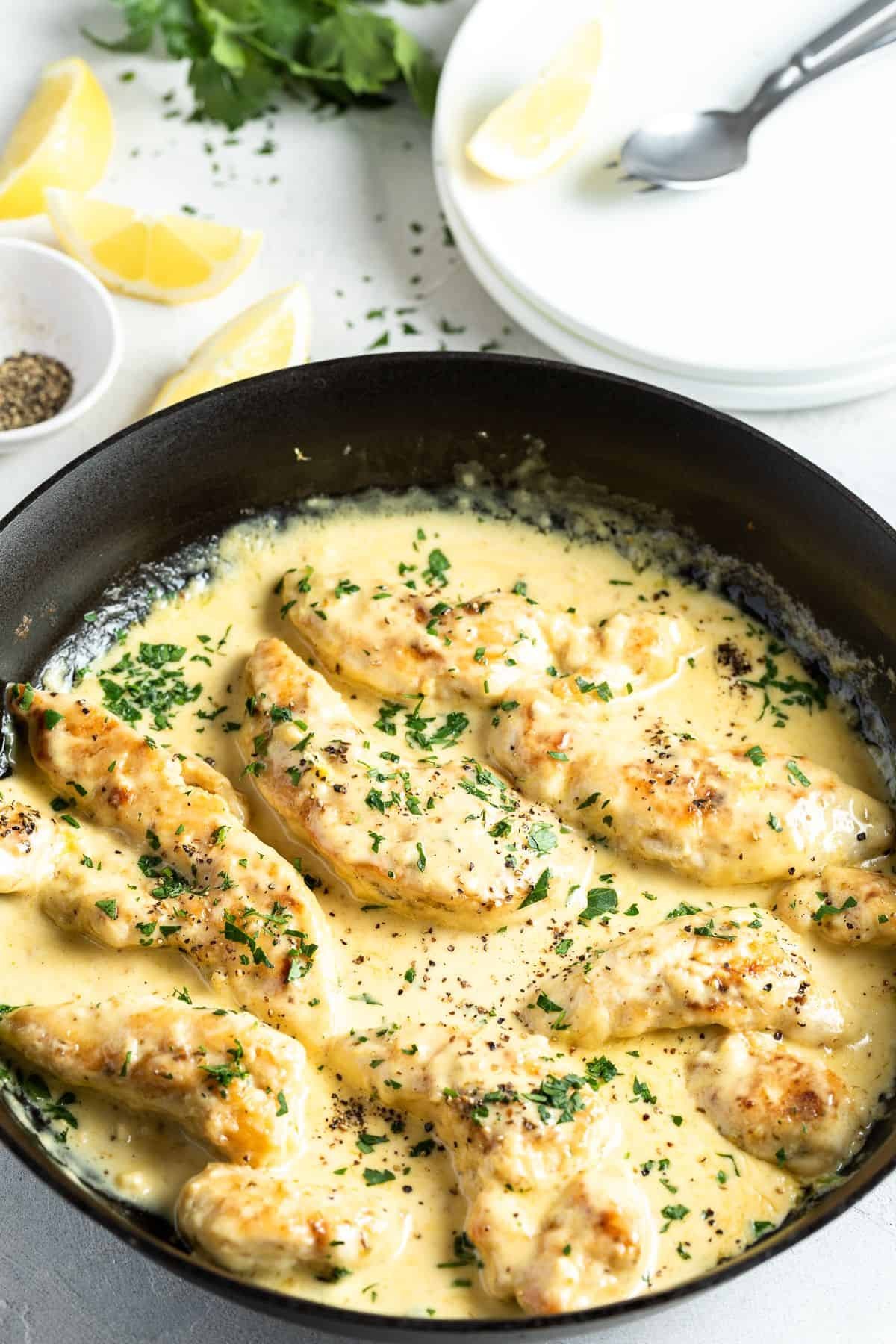 plate of creamy lemon chicken breast with fresh parsley and lemon wedges