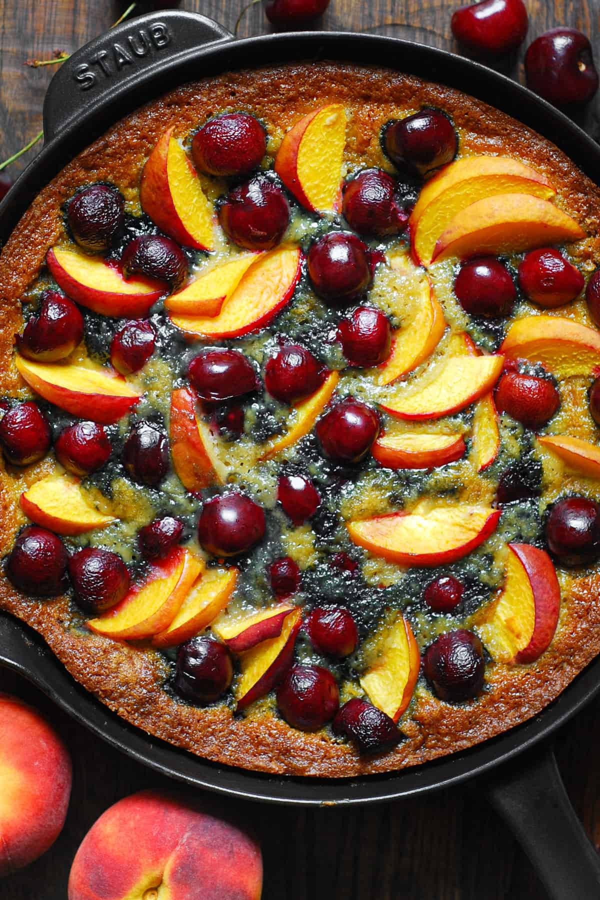 fresh peach and cherry cake on a wooden table