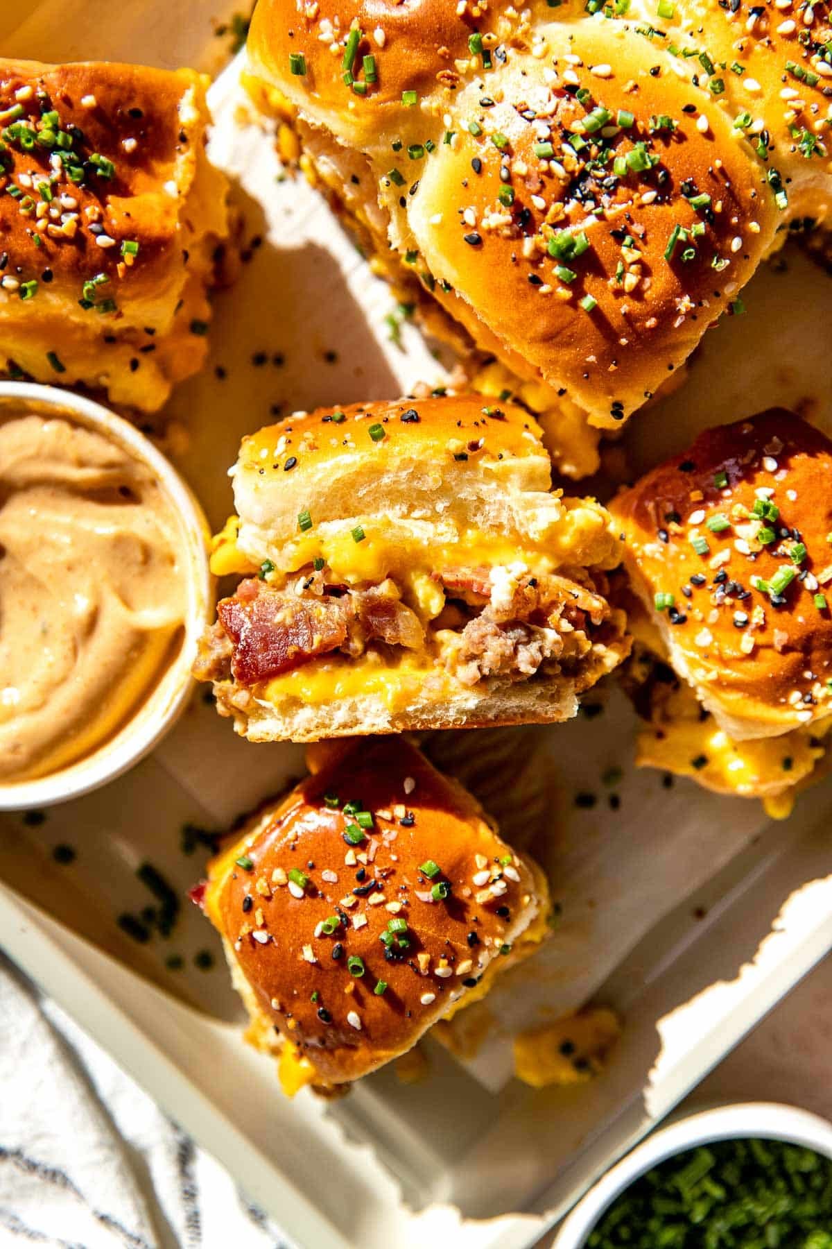 Rustic breakfast sliders with crispy bacon, fluffy eggs, melted cheddar cheese on toasted Hawaiian rolls, served on a wooden board