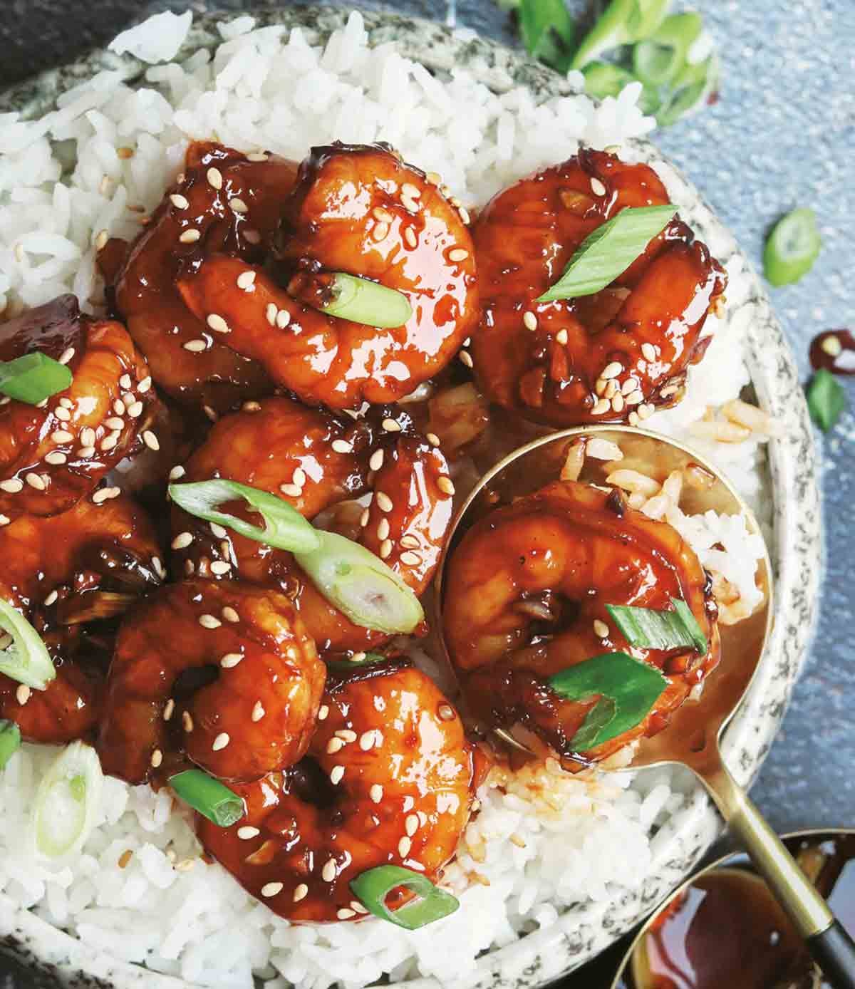 plate of sticky honey garlic shrimp with rice and green onions