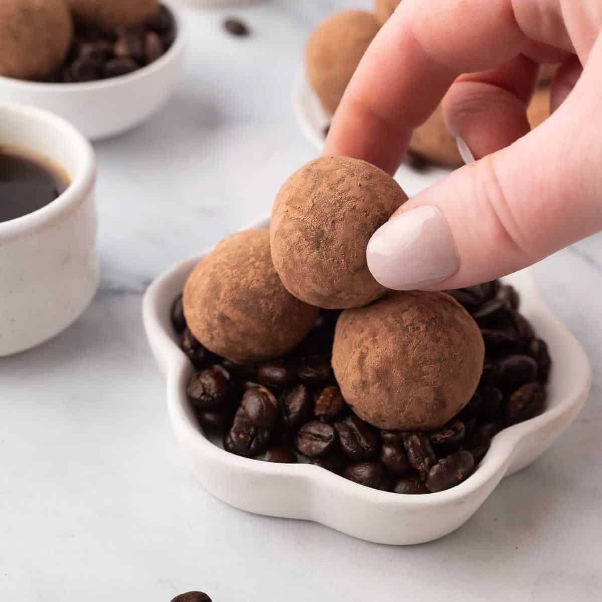 Handmade espresso chocolate truffles dusted with cocoa on a rustic wooden board, a small cup of espresso in the background