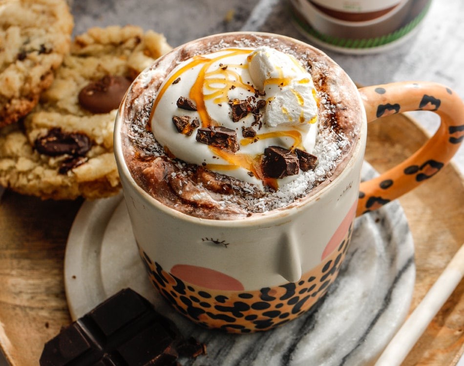Gourmet coconut hot chocolate with whipped tropical fruit cream, cozy setting, steam rising, close-up