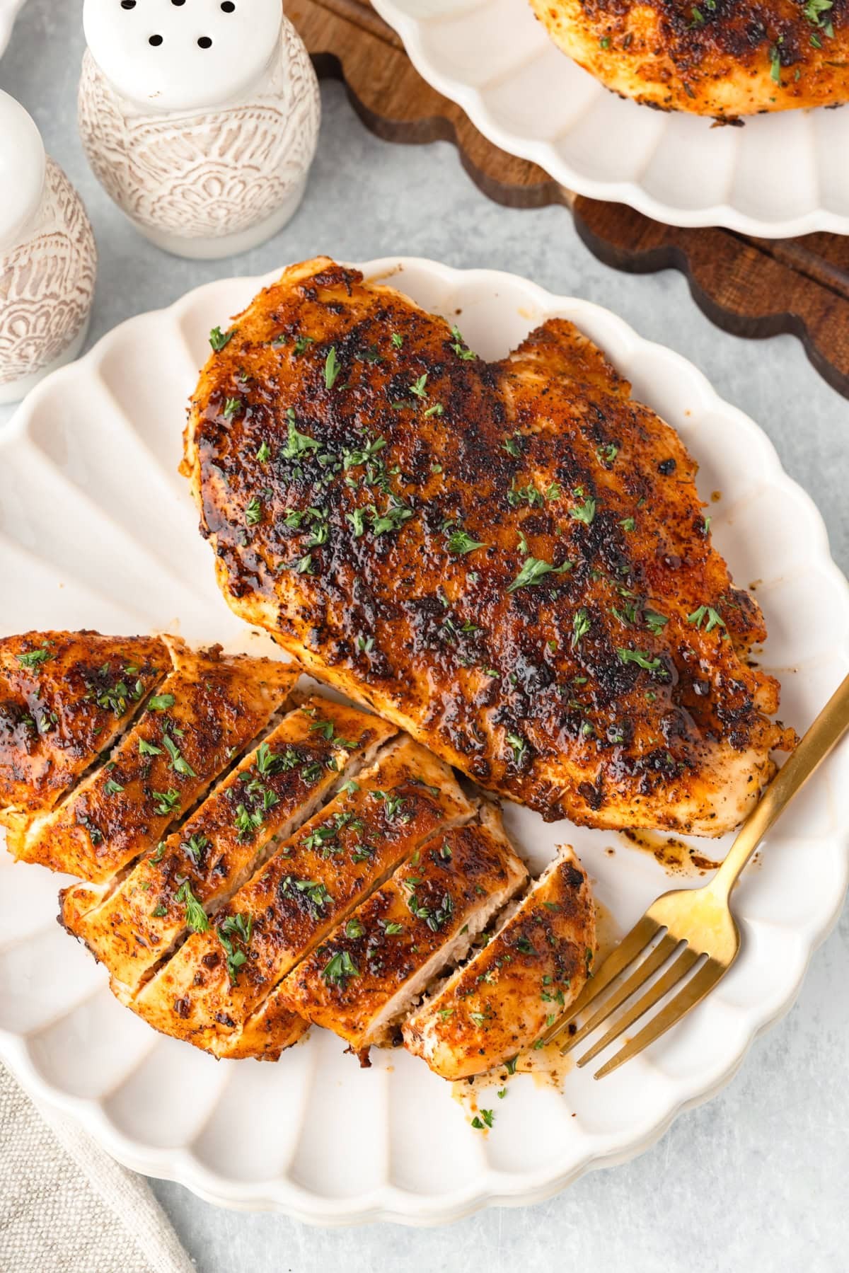 Golden brown cream-seared chicken breast on a plate with fresh herbs
