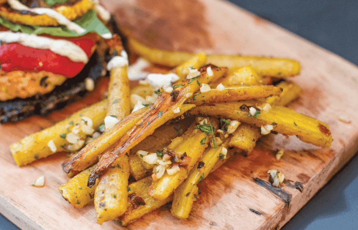 garlic herb roasted carrot fries on a wooden board