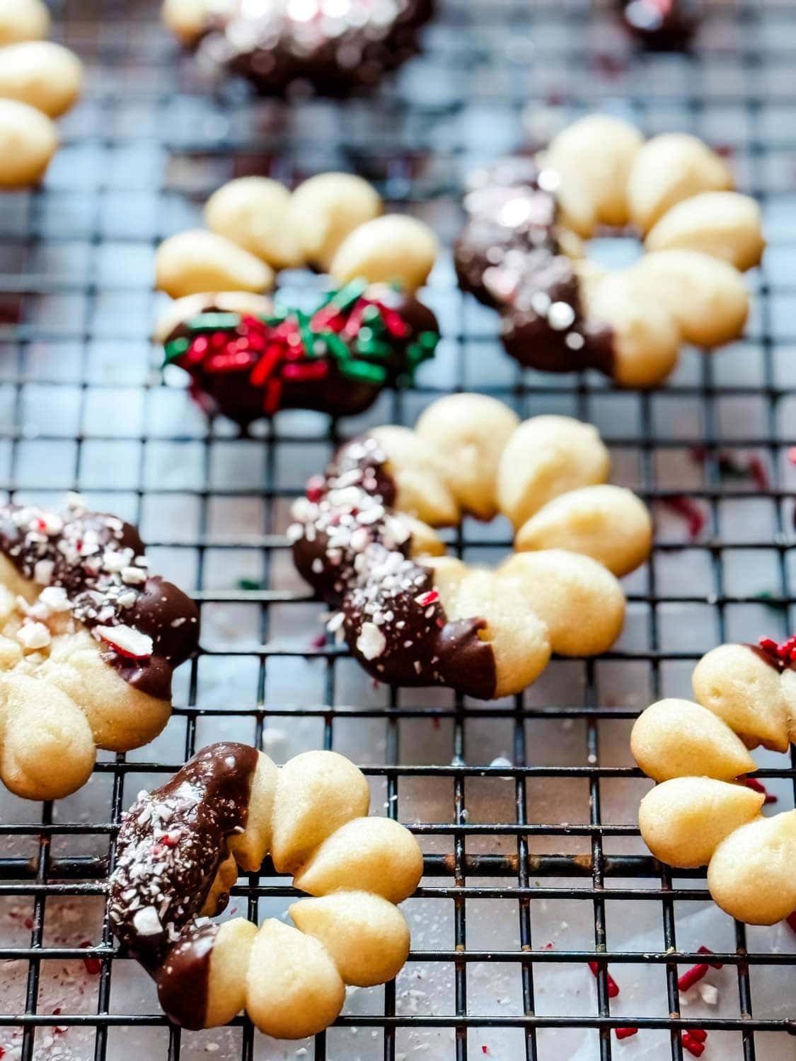 Festive butter spritz cookies with sprinkles on a cooling rack, holiday background