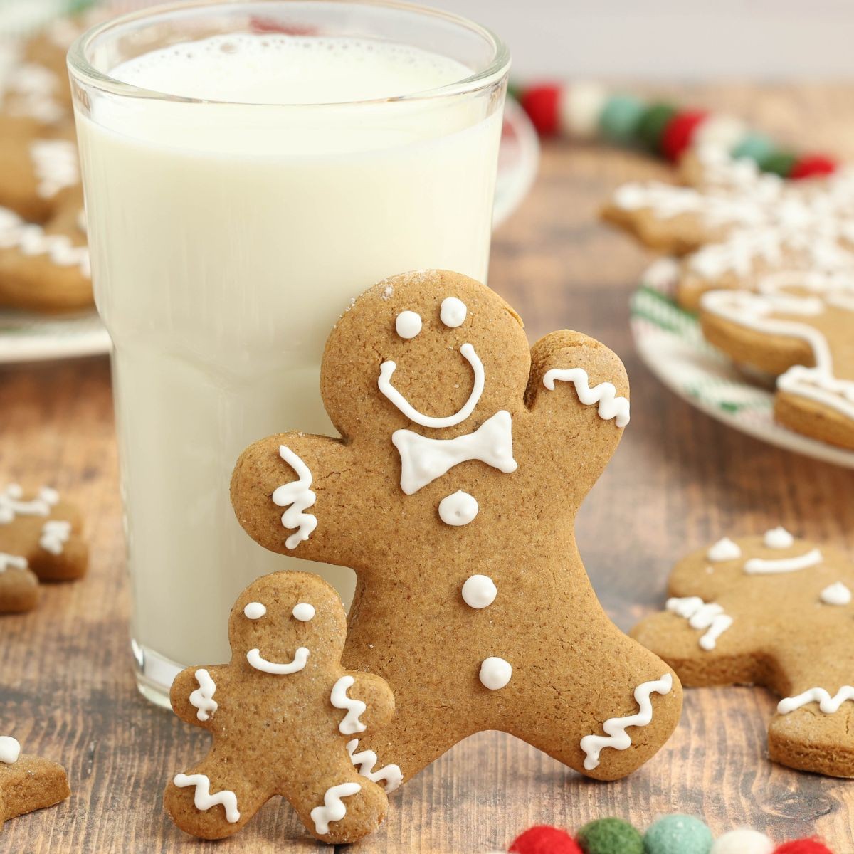 freshly baked gingerbread cookies with elaborate white icing decorations on a rustic wooden table, cozy holiday setting