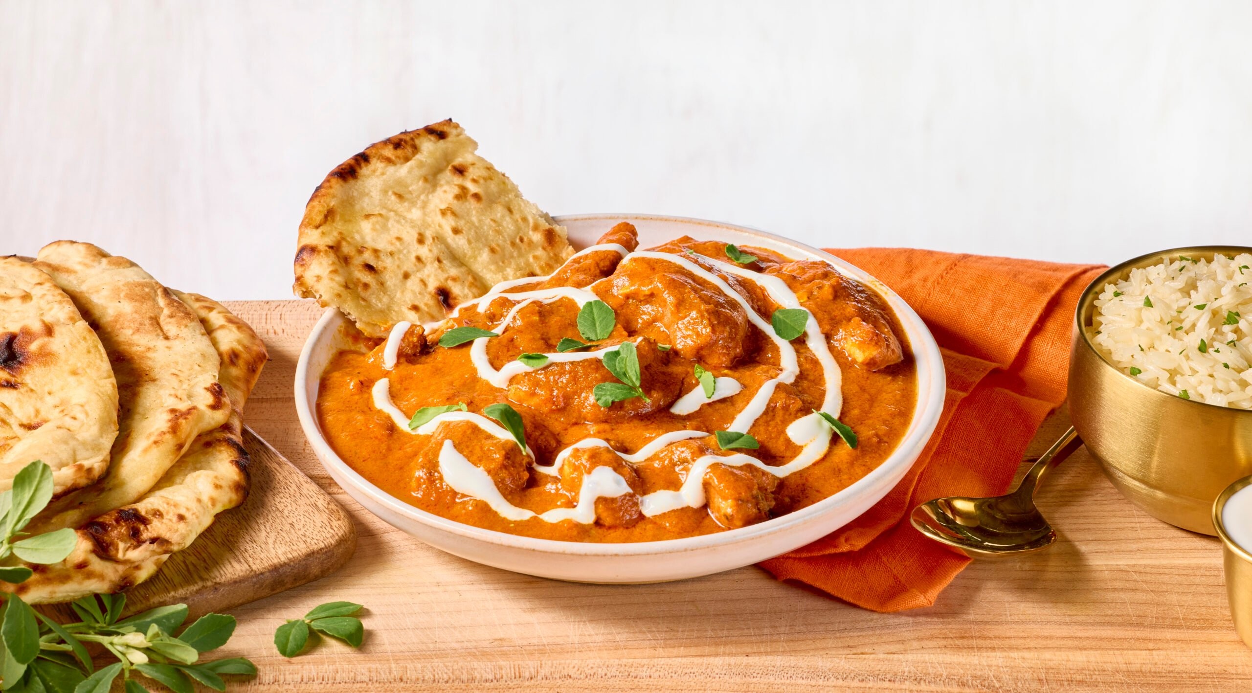 Creamy slow-simmered butter chicken in a traditional Indian serving dish with naan bread