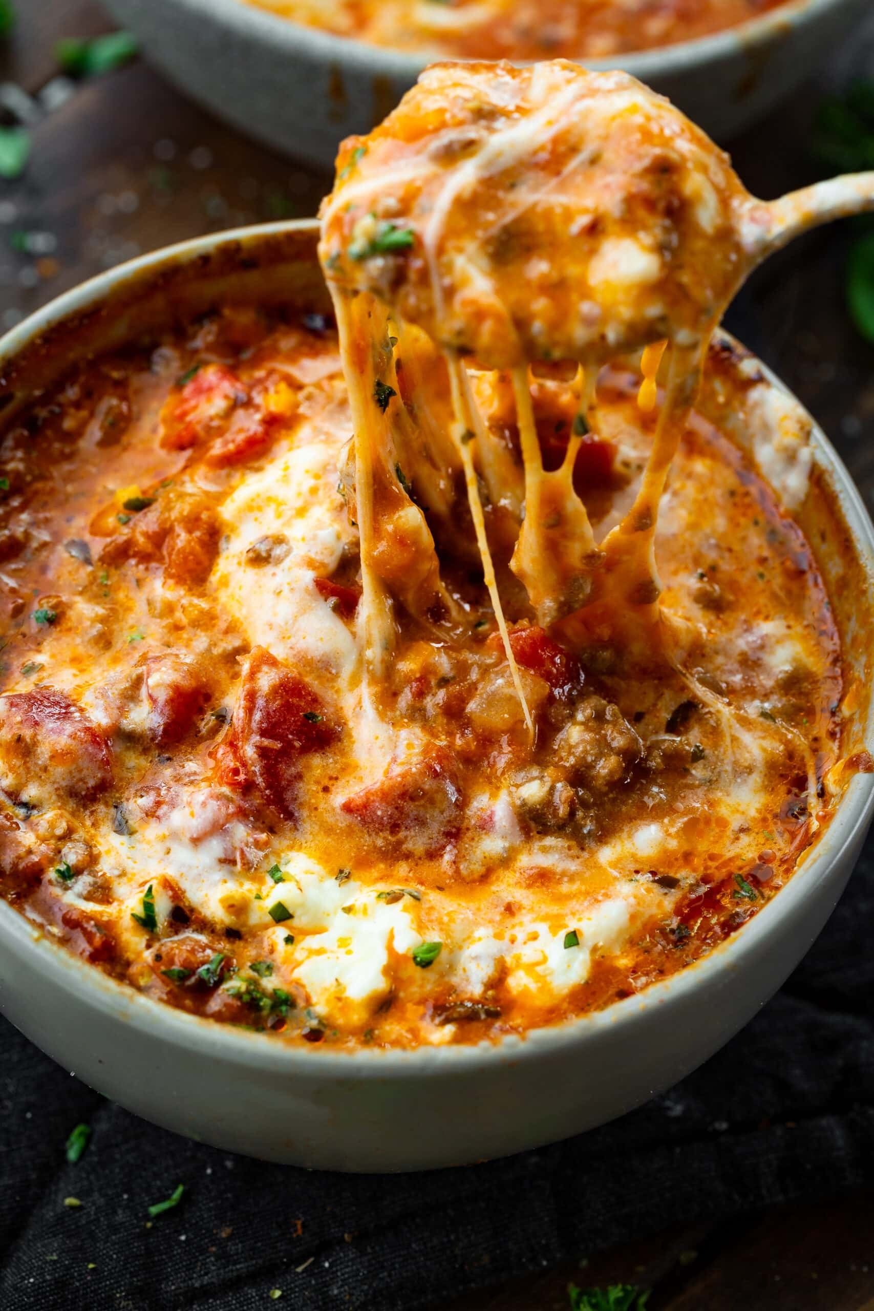 hearty bowl of lasagna soup with melted mozzarella and fresh basil on a rustic wooden table, cozy lighting
