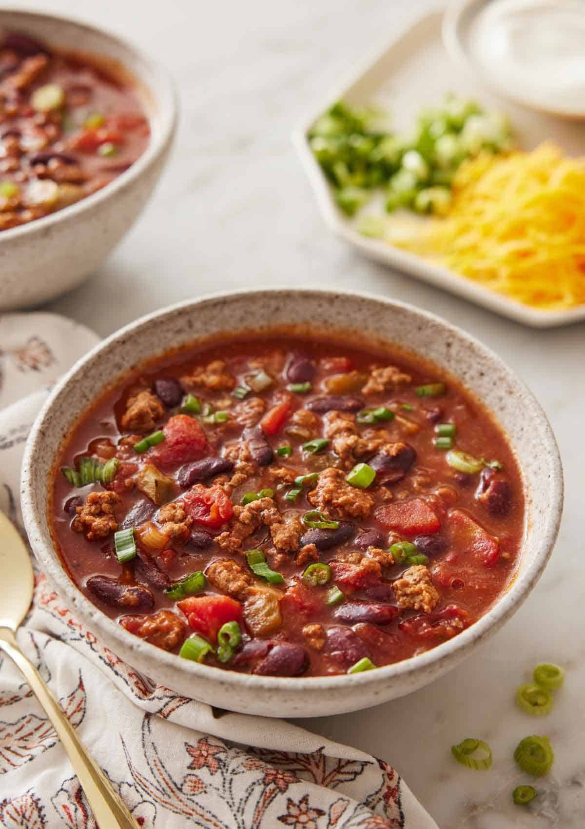A steaming bowl of slow cooker chili with toppings