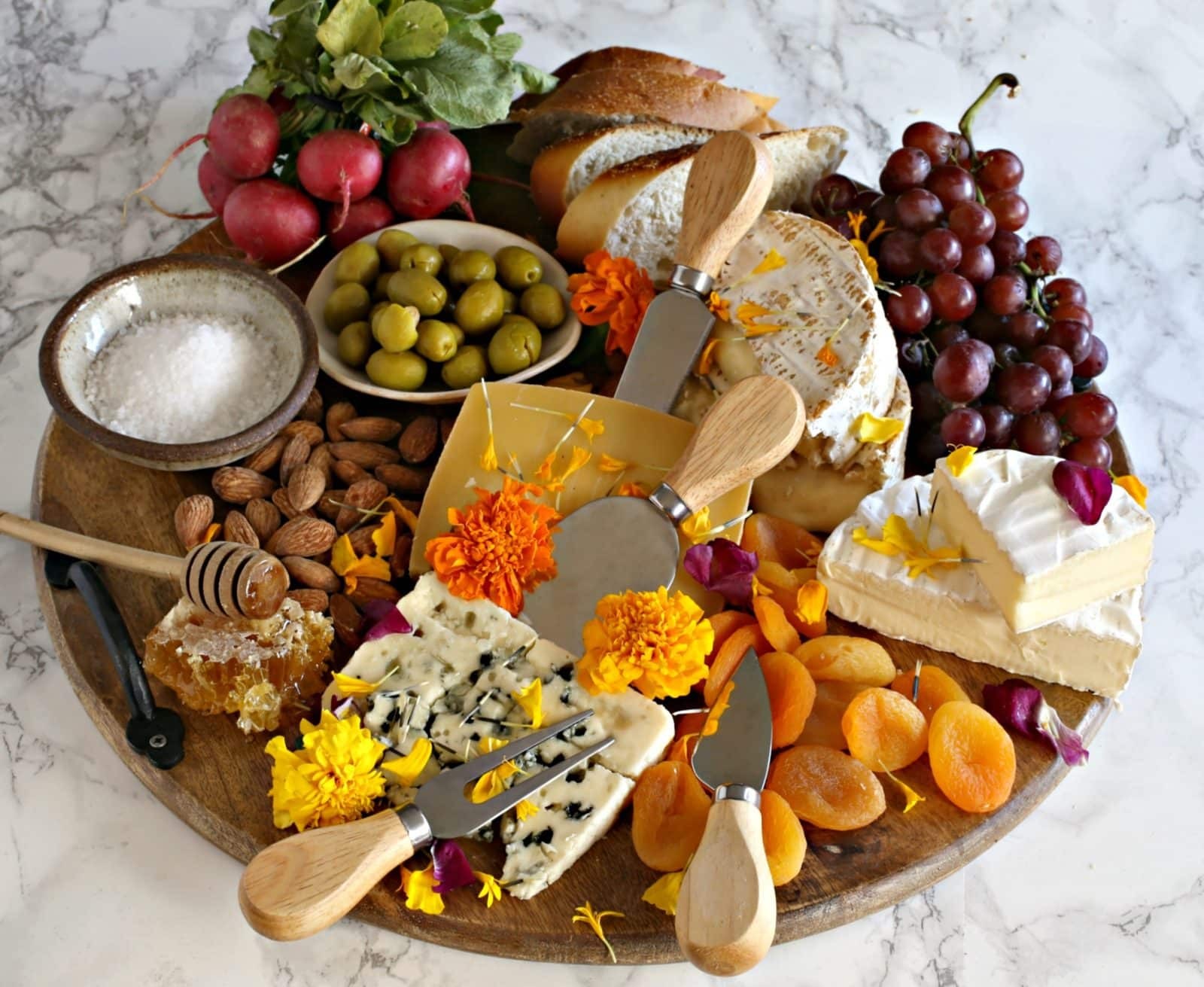 overhead shot of a beautifully arranged cheese platter with edible flowers and herbs