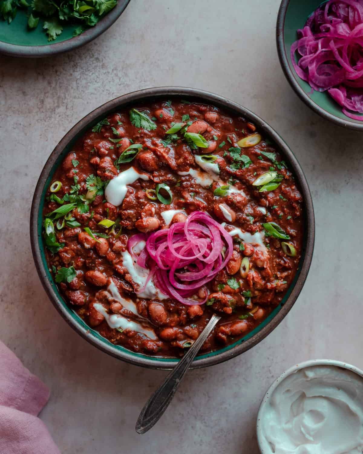 bowl of spicy vegan chili topped with cilantro and red onion