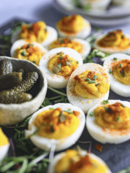 Perfect deviled eggs with smoked paprika and chives garnish, served on a rustic wooden platter