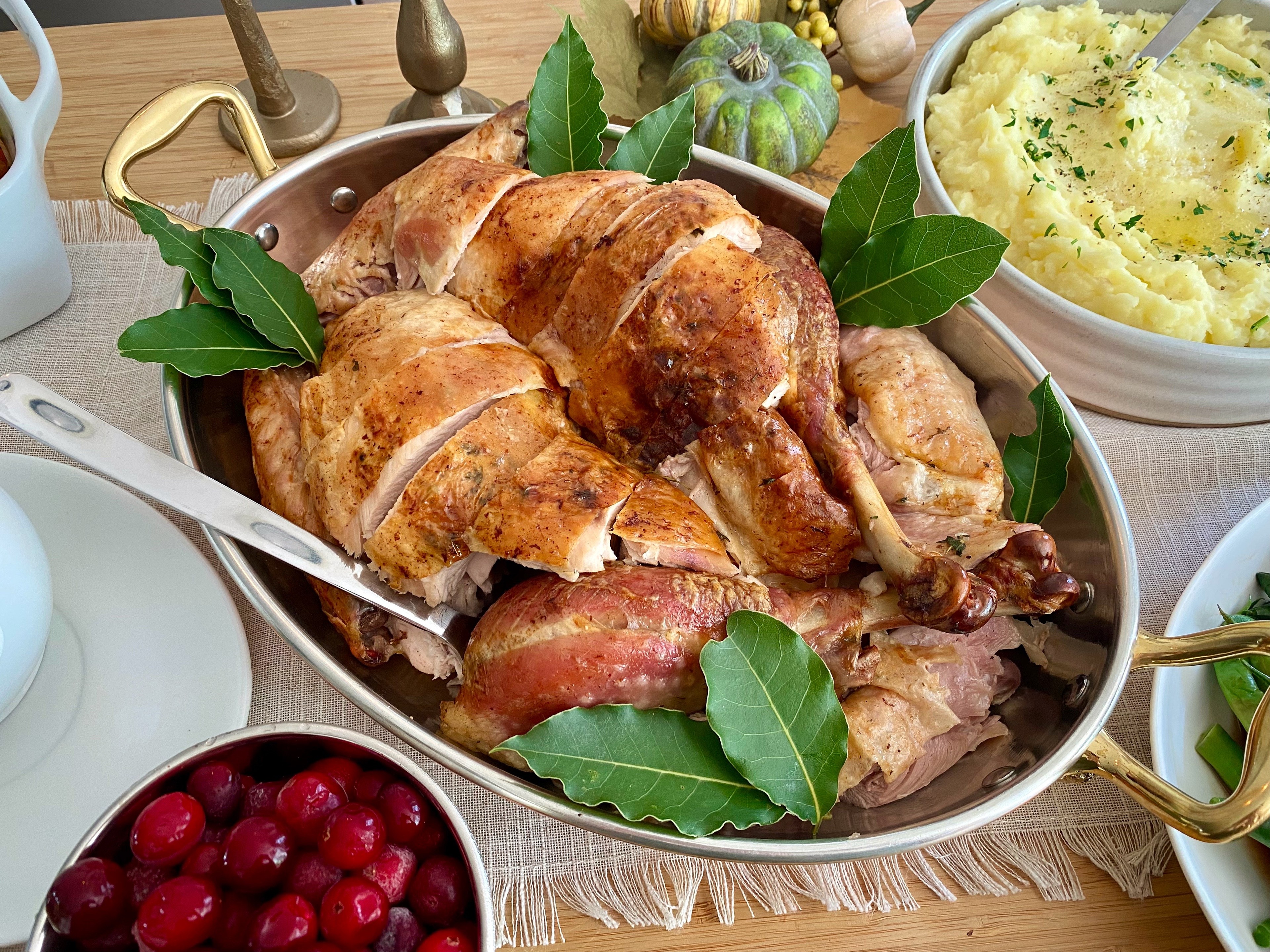 Golden brown slow-roasted butter herb turkey on a festive platter with mashed potatoes and gravy, bokeh background