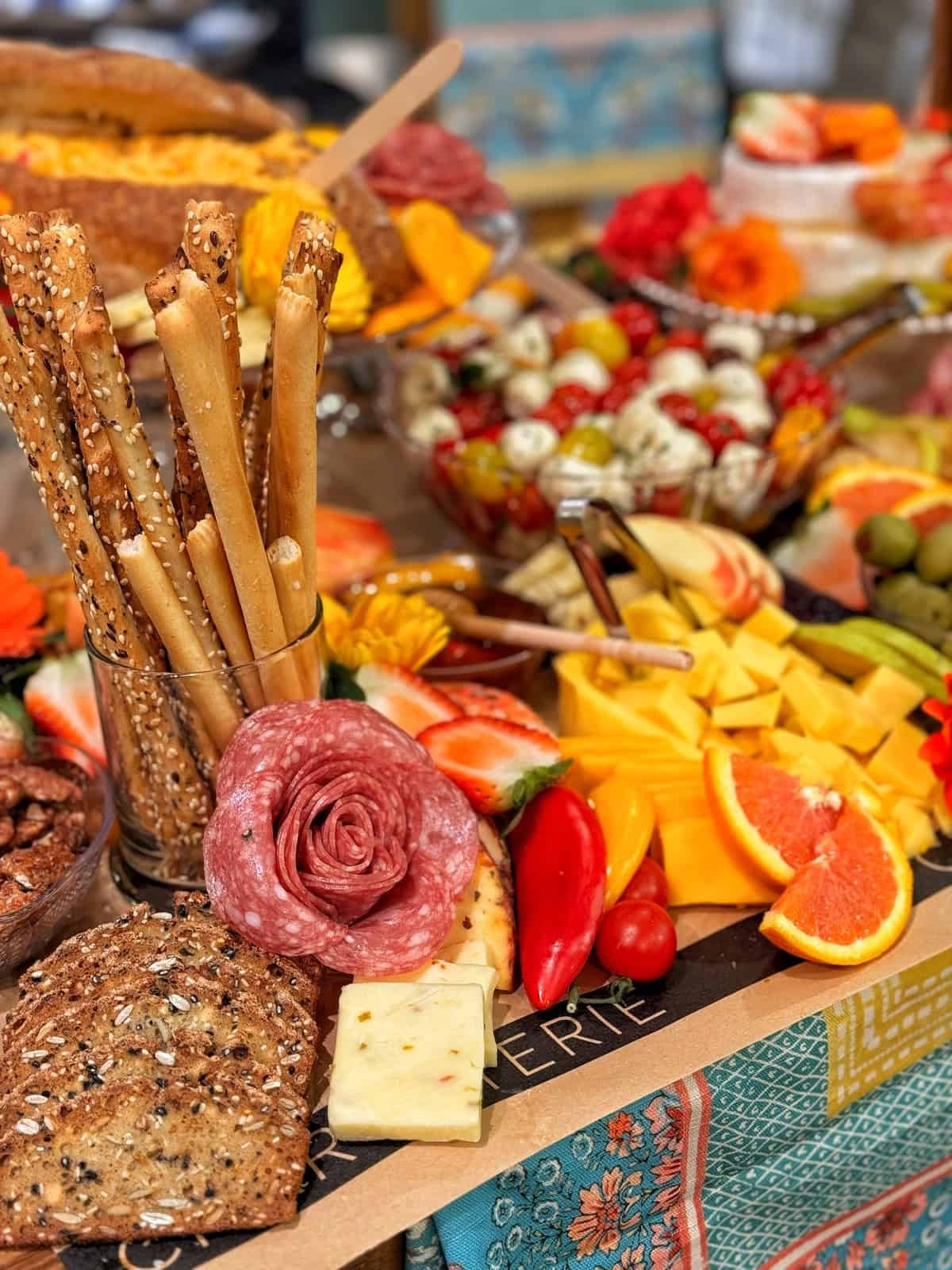 Vibrant garden charcuterie board with fresh vegetables, fruit, cheese, and dips, artfully arranged on a wooden platter for a casual gathering