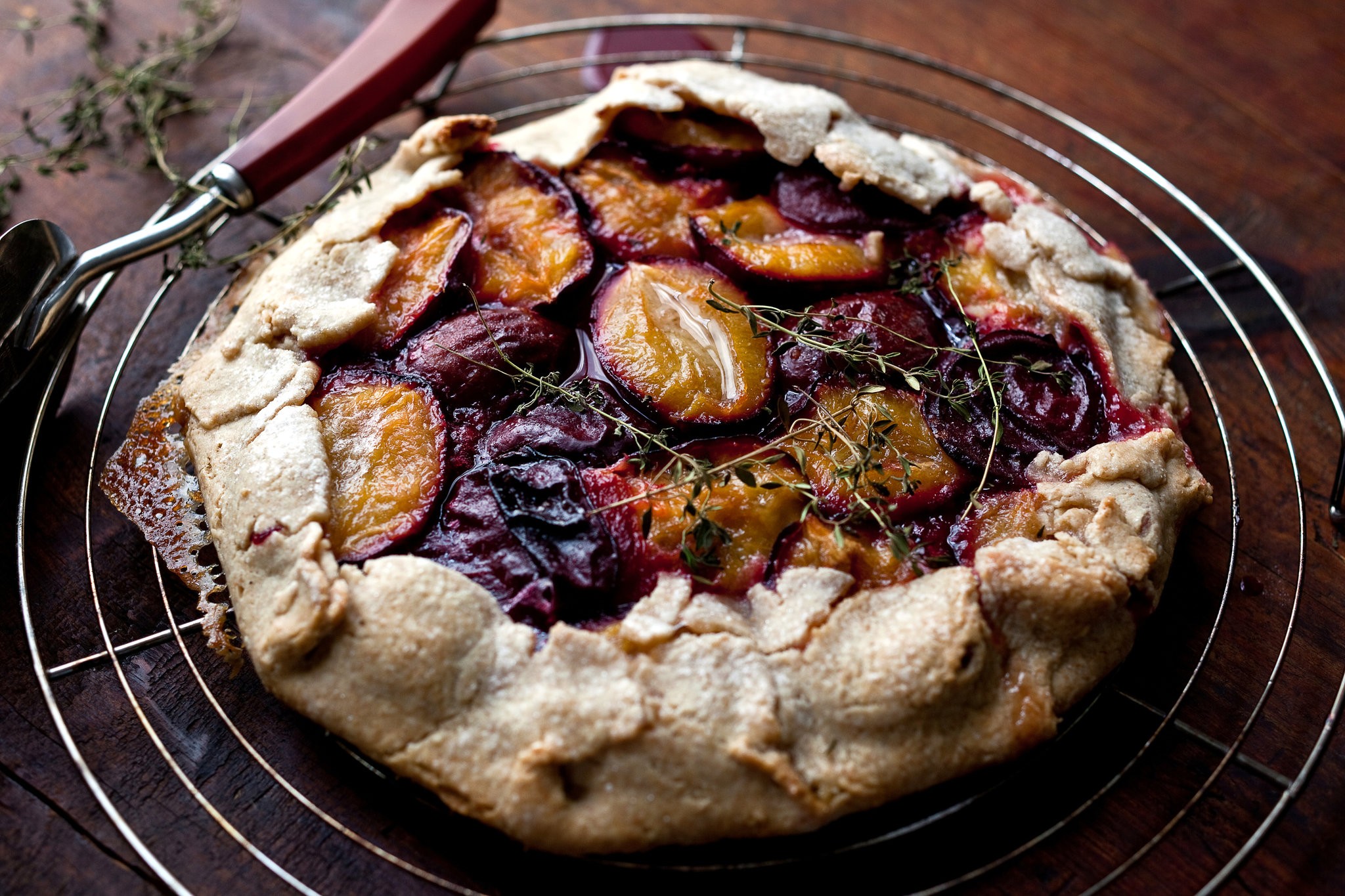 rustic thyme plum tart on a wooden table