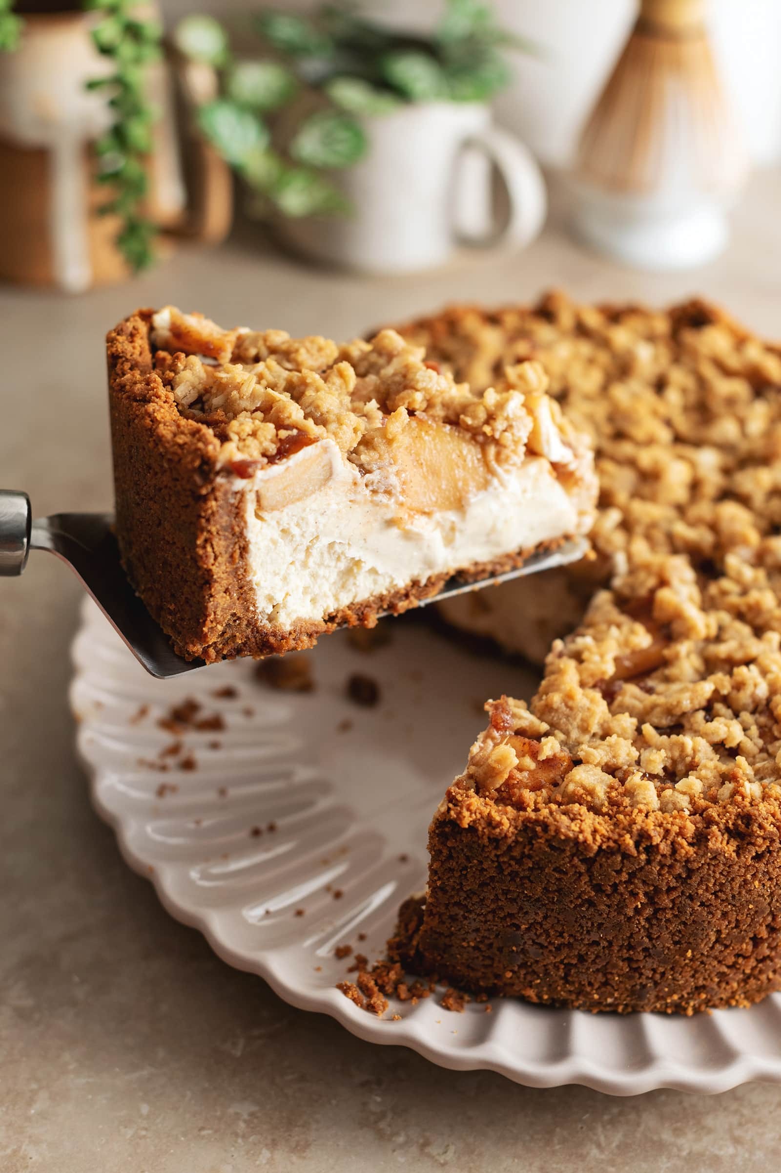 slice of apple crumble cheesecake on a rustic wooden table with fall foliage