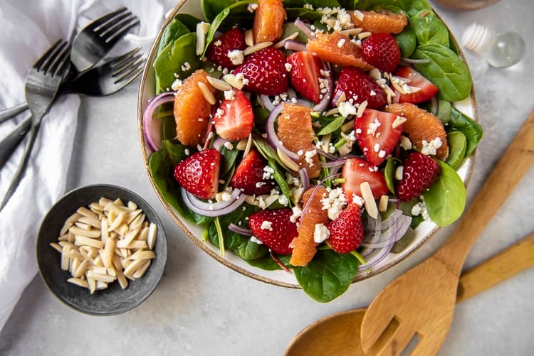 close up of a vibrant strawberry spinach salad with a citrus dressing drizzled on top