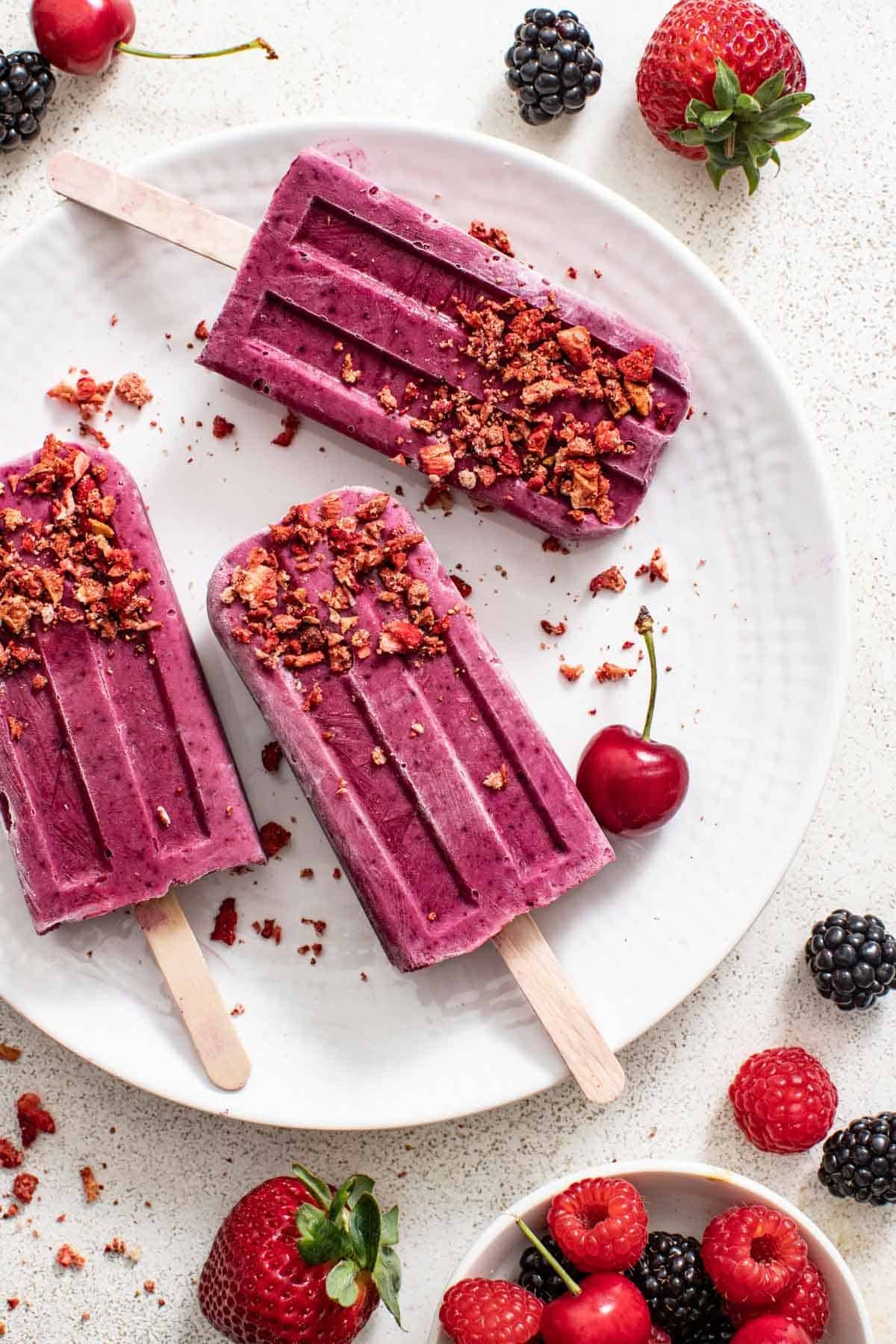 brightly lit sugar plum protein popsicles with fresh berries