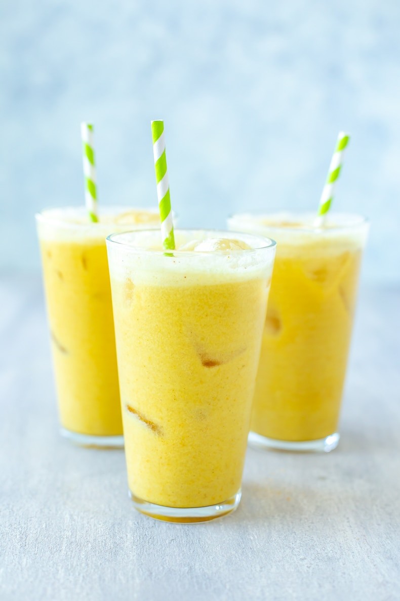 iced golden ginger drink in a glass with ginger slices