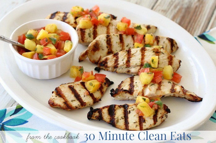 Grilled pineapple salsa chicken breasts on a wooden platter