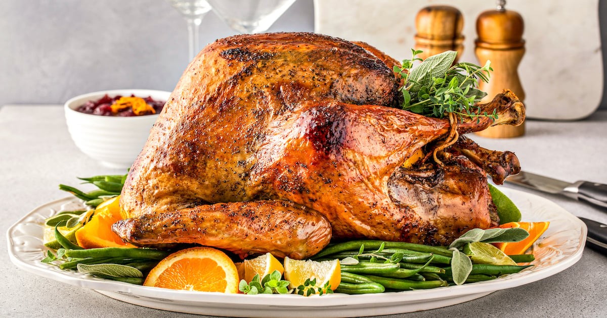Close-up of a perfectly roasted turkey with crispy, golden-brown, pepper-rubbed skin on a platter