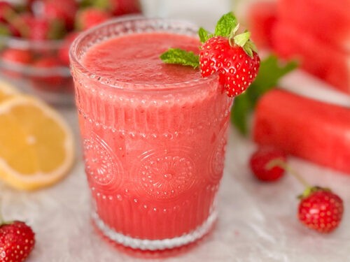 vibrant strawberry jasmine smoothie in a glass with fresh ingredients around