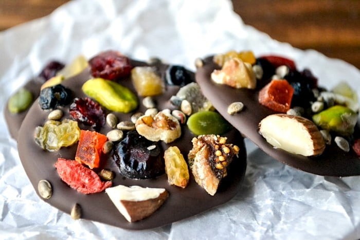 beautiful dark chocolate mendiants with assorted dried fruits and nuts on parchment paper