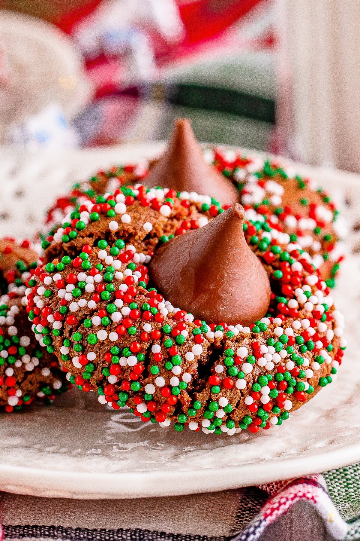 close-up chocolate cookies with vibrant festive icing and sprinkles, cozy holiday setting