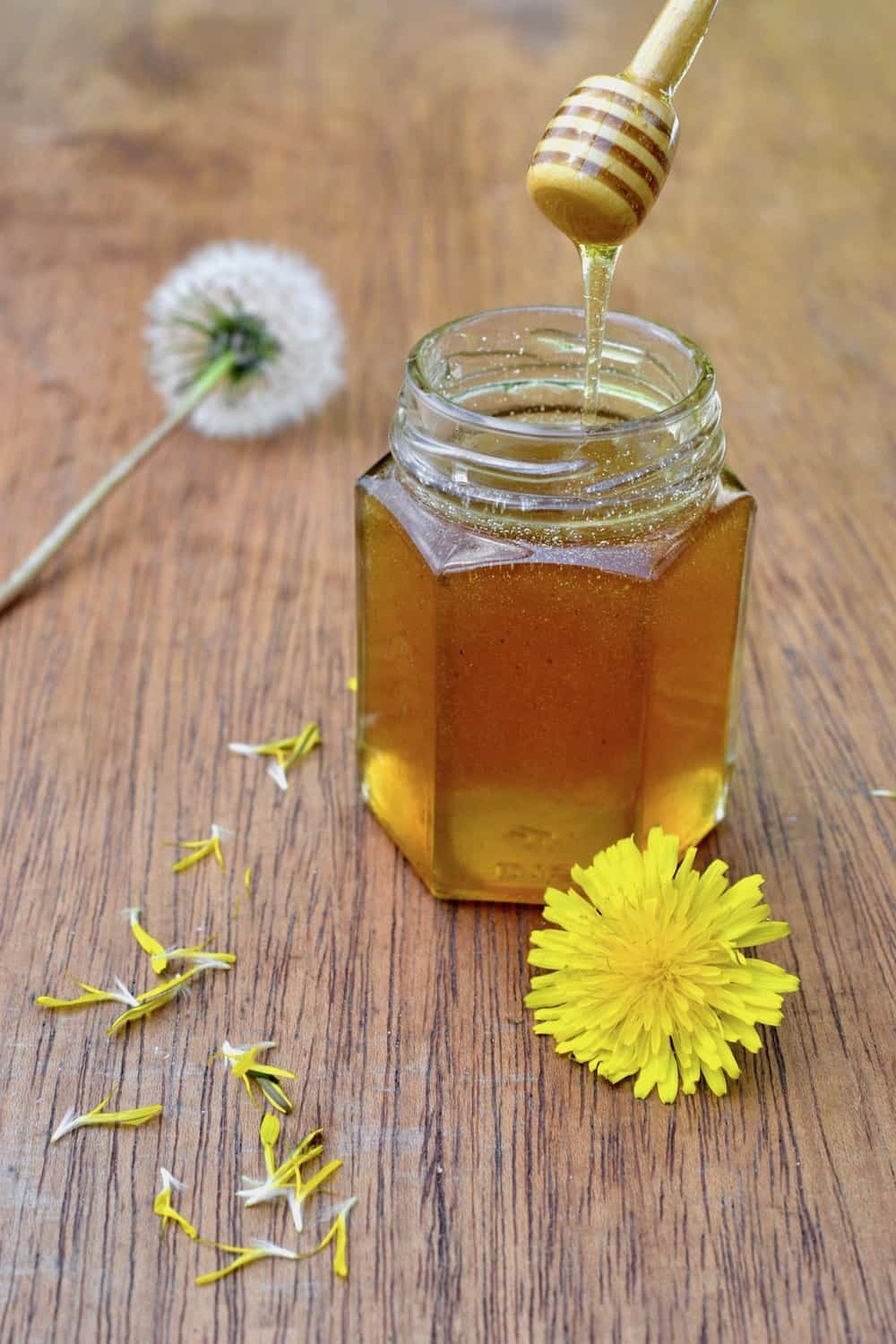 dandelion honey dew lassi in a glass with dandelions around it