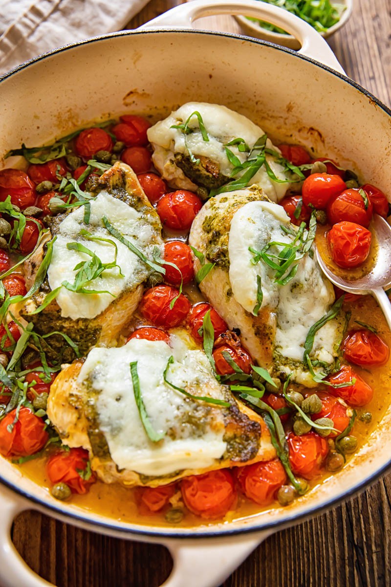 Pesto chicken protein bowl with cherry tomatoes and mozzarella served in a rustic setting