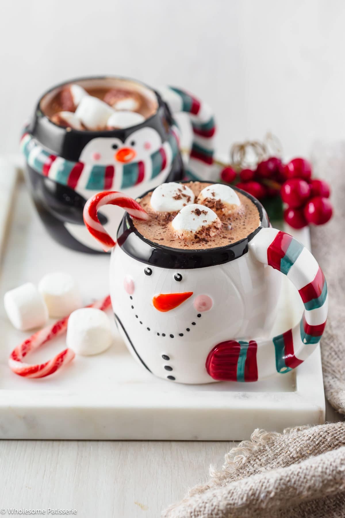 Peppermint hot chocolate in a festive mug with marshmallows and candy canes, cozy setting, steam rising.