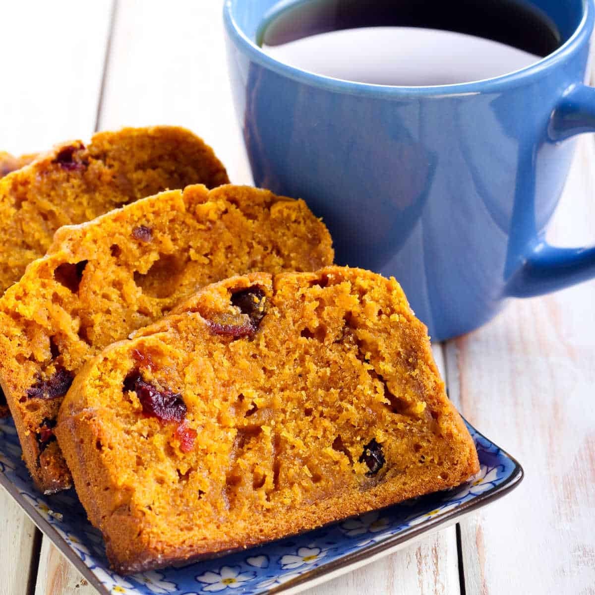 slice of pumpkin bread with nuts and a cup of coffee