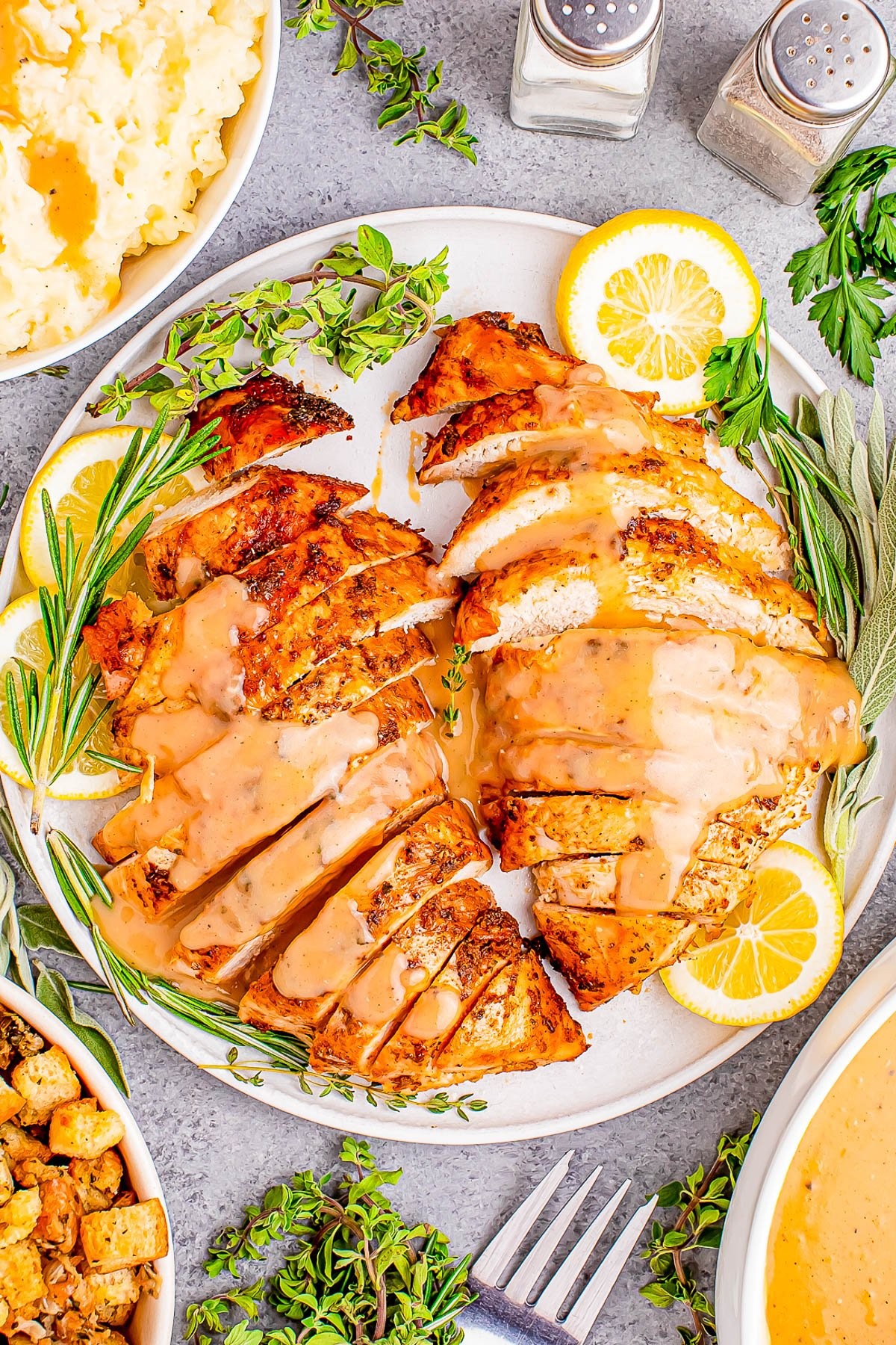 Close-up of golden brown pan-seared turkey breast slices with lemon butter sauce and fresh herbs, garnished on a plate