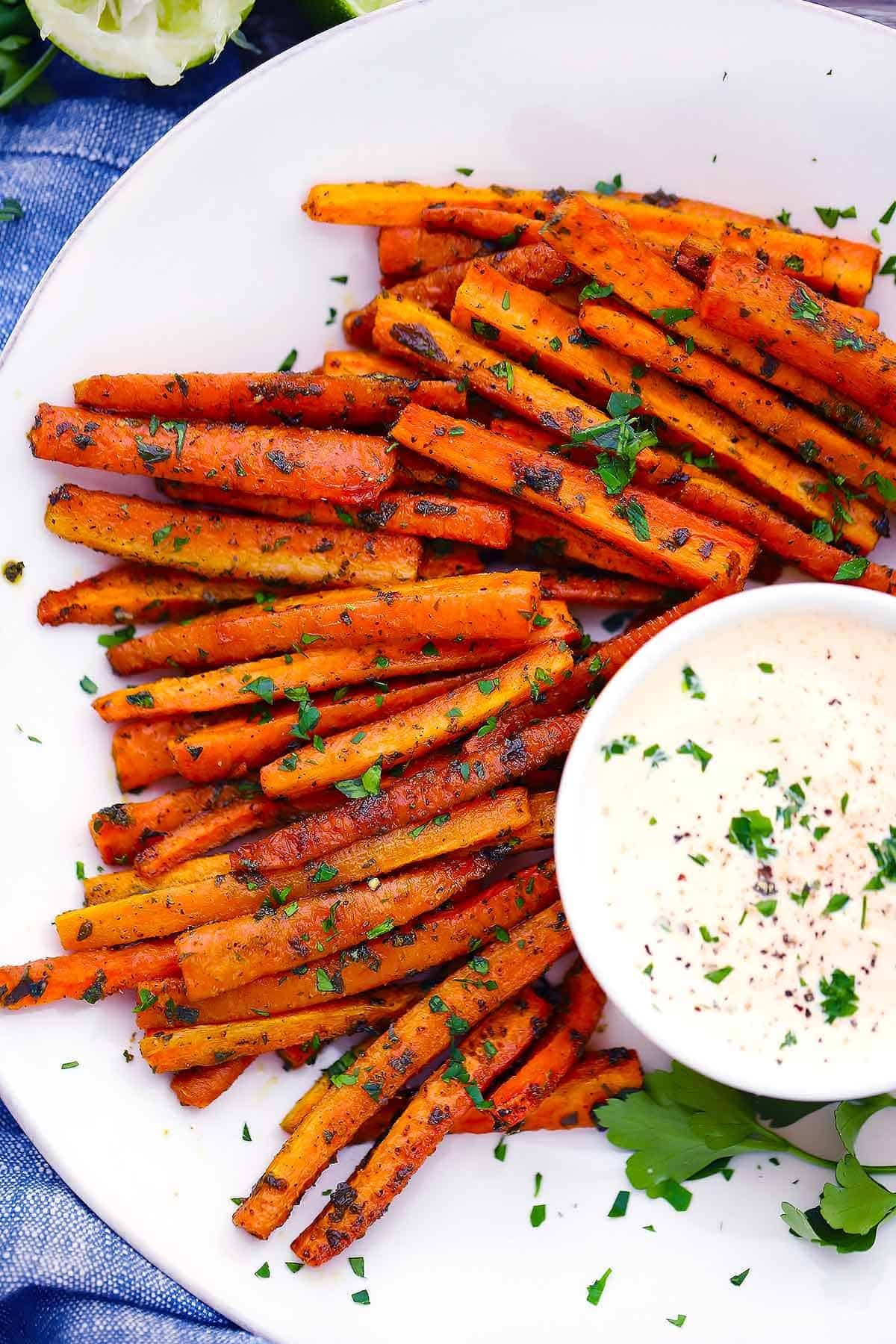 Spicy peanut carrot fries on a plate with dipping sauce