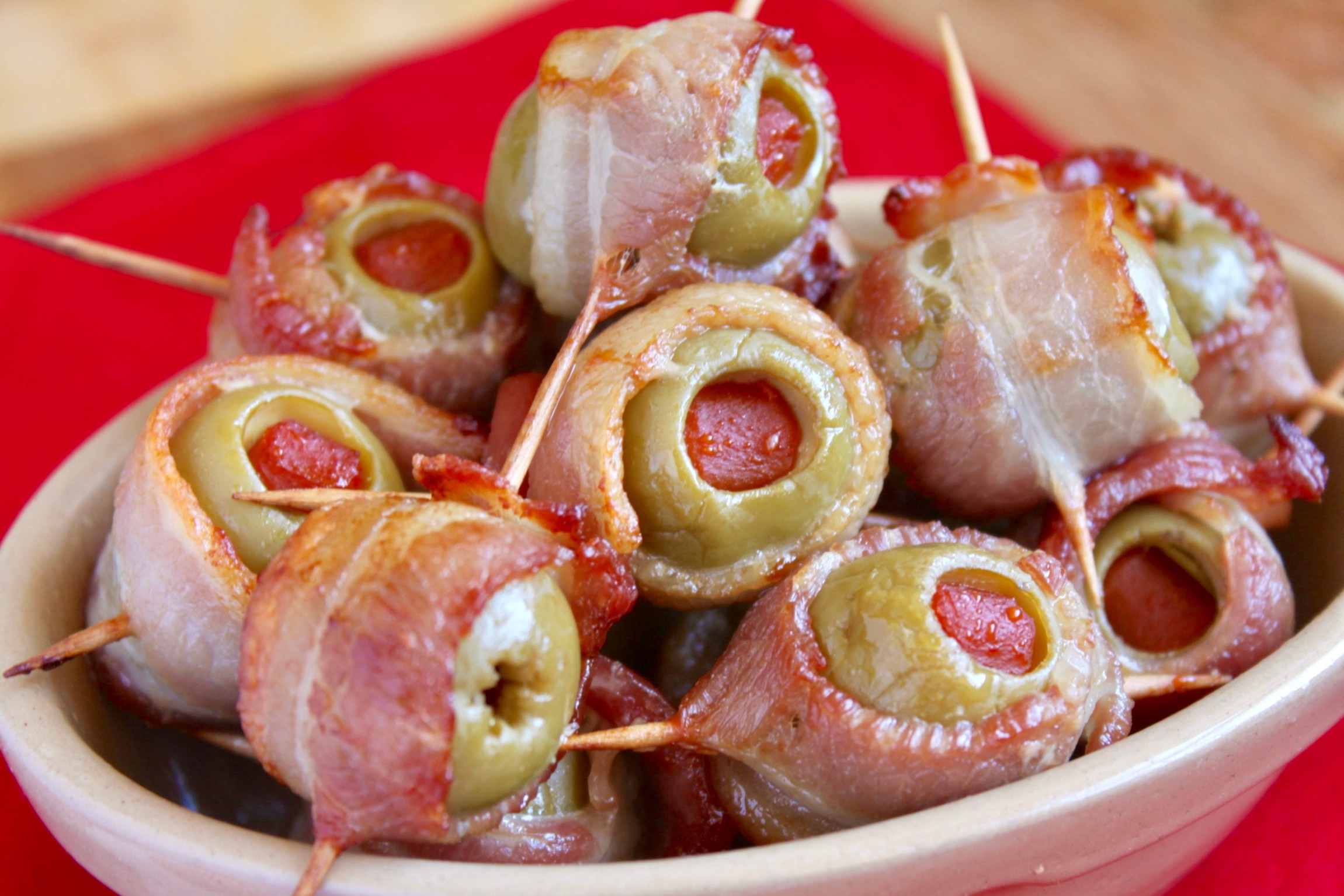 bacon wrapped olives with cream cheese on a serving platter