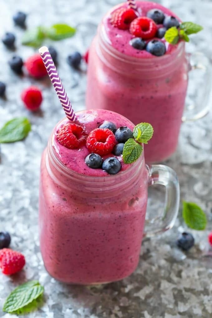 vibrant summer berry and yogurt smoothie in a glass with fresh berries around