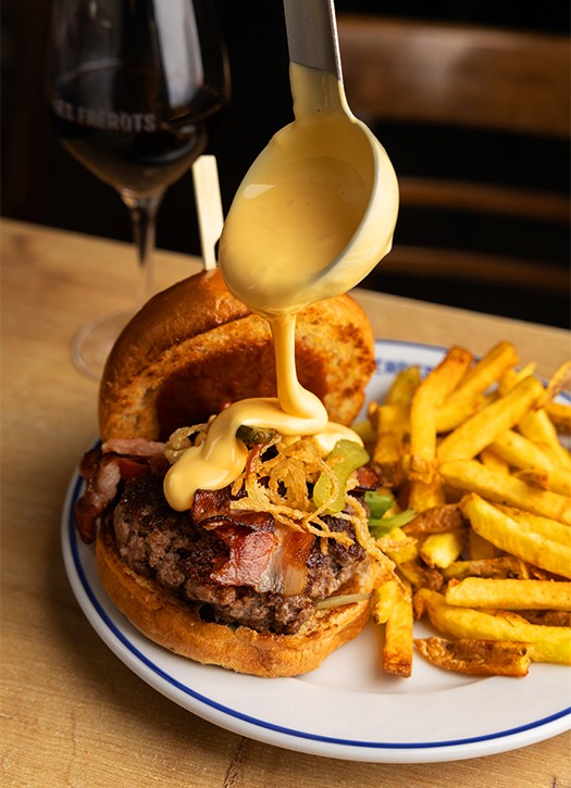 Gourmet smash burger with melted cheese and secret sauce dripping, served with crispy fries